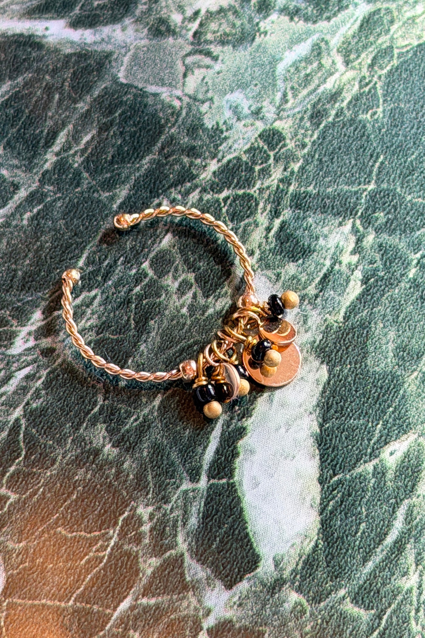 Fino anillo dorado con pequeños charms de perlas negras.