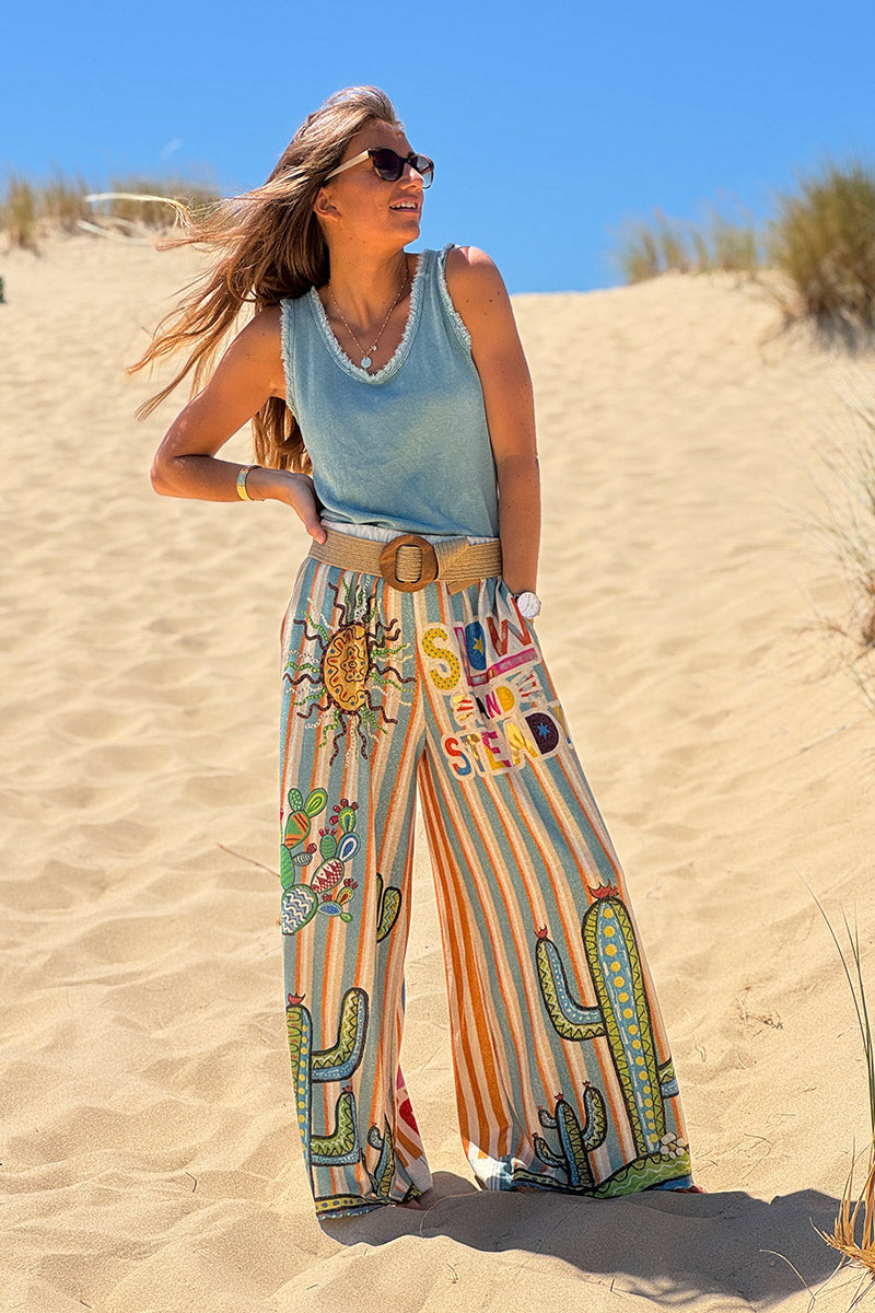 Pantalón ancho brillante, cómodo y flexible con estampado de rayas naranjas y azules de sol y cactus.