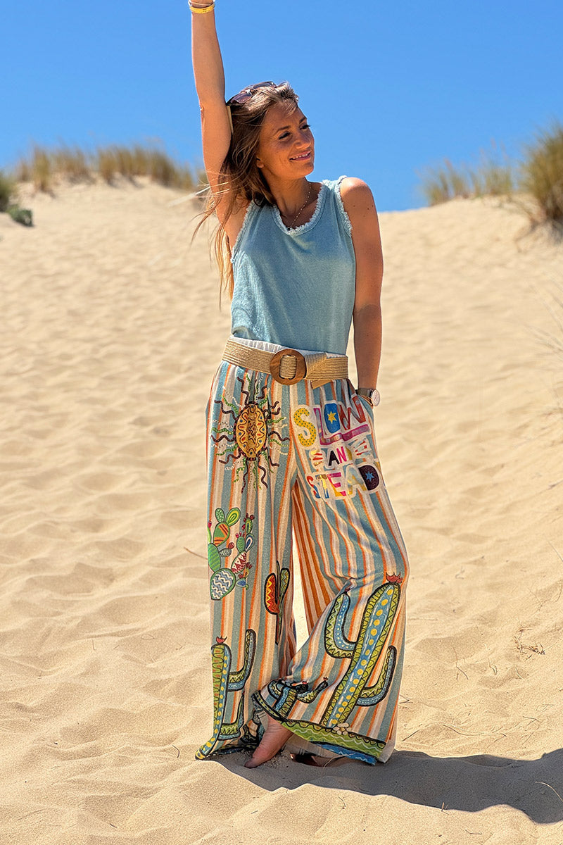 Pantalón ancho brillante, cómodo y flexible con estampado de rayas naranjas y azules de sol y cactus.