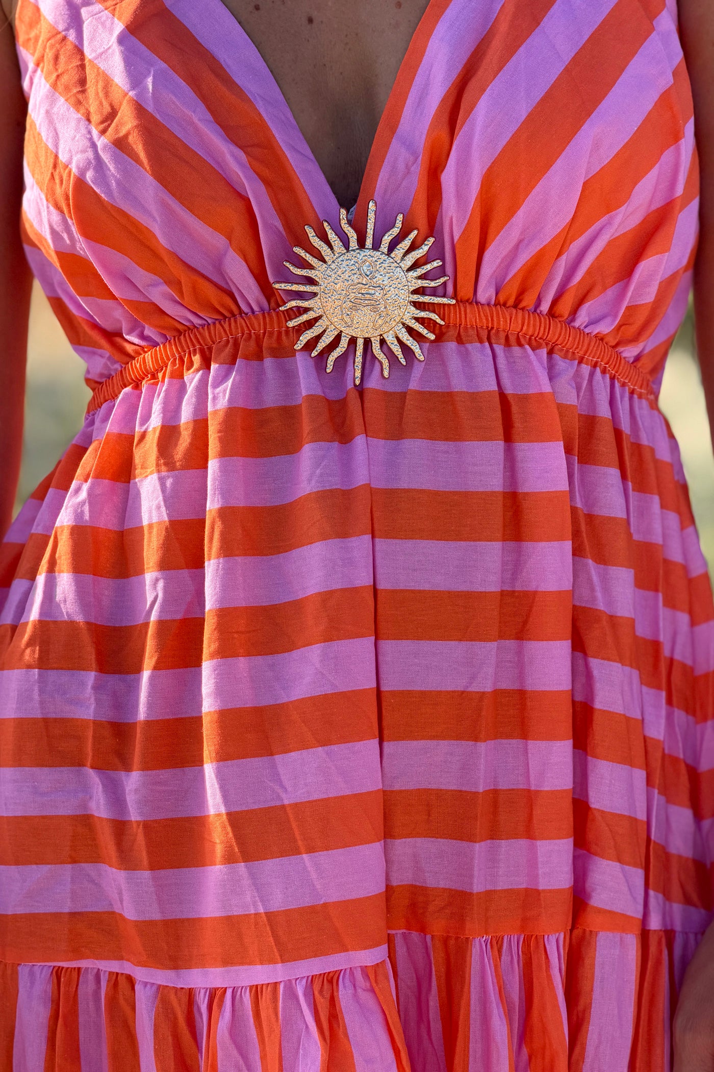 Robe longue à bretelles en coton motifs rayures orange et rose broche soleil doré