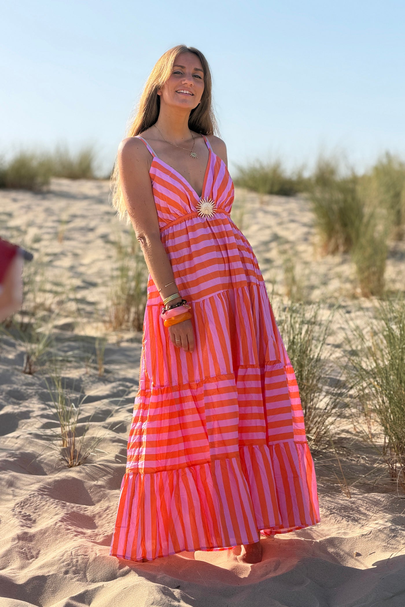 Robe longue à bretelles en coton motifs rayures orange et rose broche soleil doré