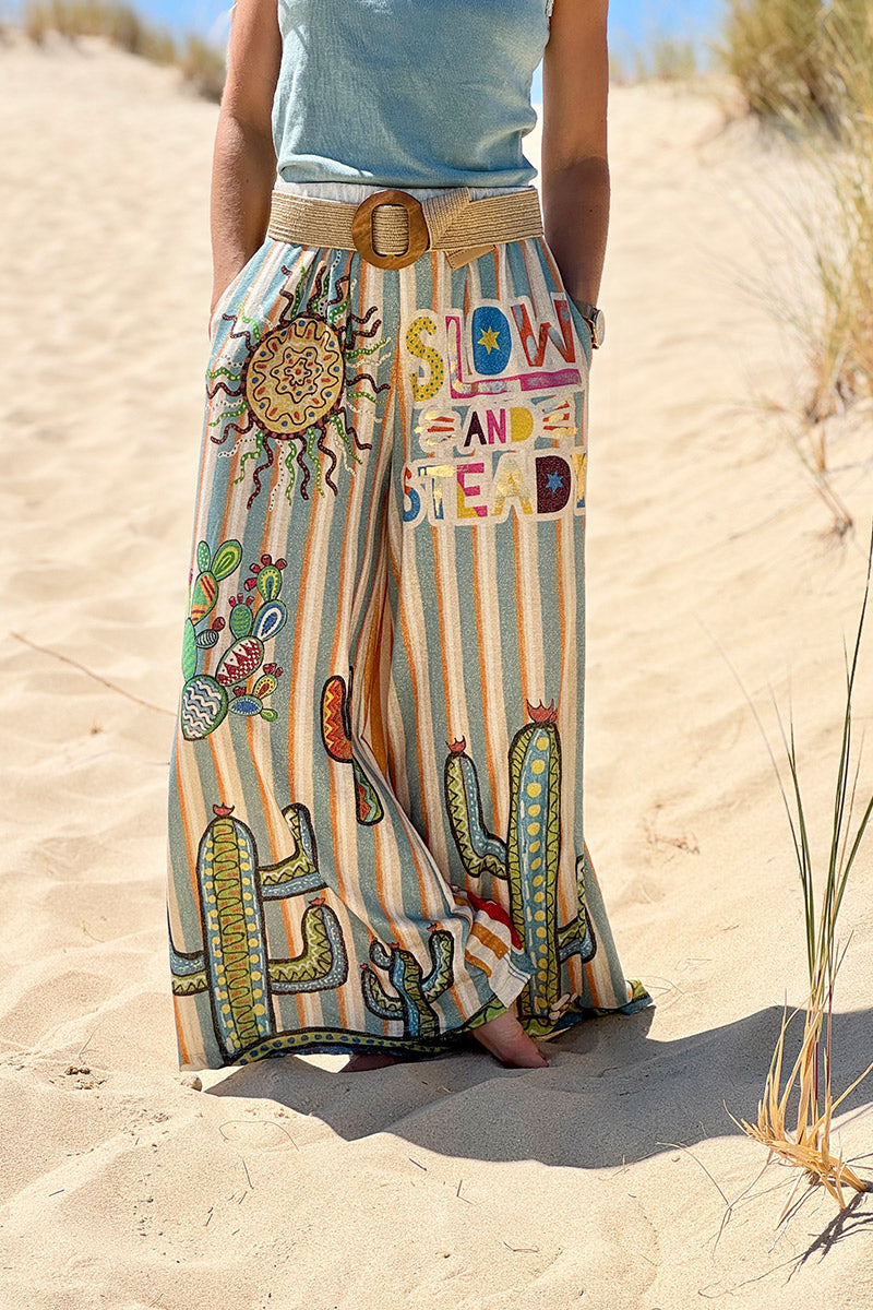 Pantalón ancho brillante, cómodo y flexible con estampado de rayas naranjas y azules de sol y cactus.
