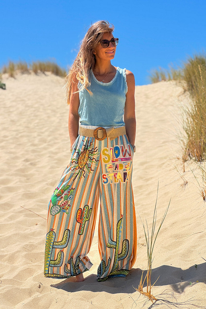 Pantalón ancho brillante, cómodo y flexible con estampado de rayas naranjas y azules de sol y cactus.