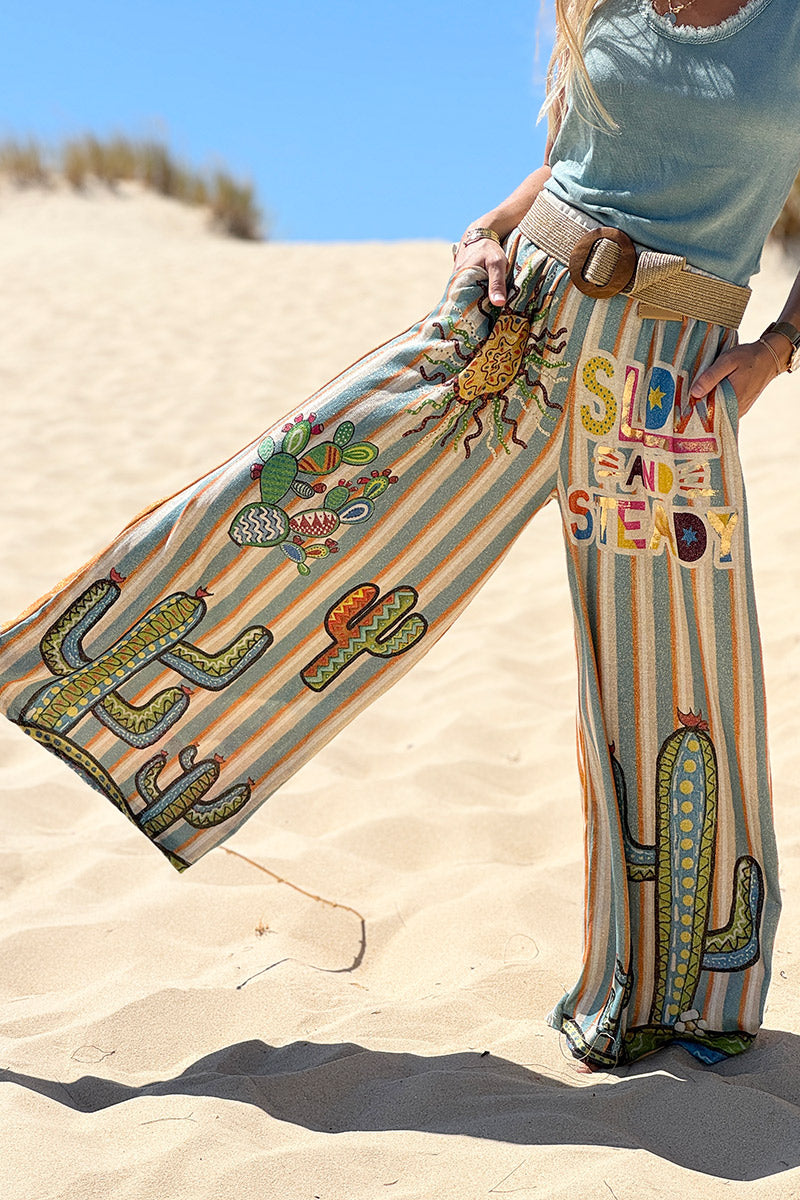 Pantalón ancho brillante, cómodo y flexible con estampado de rayas naranjas y azules de sol y cactus.