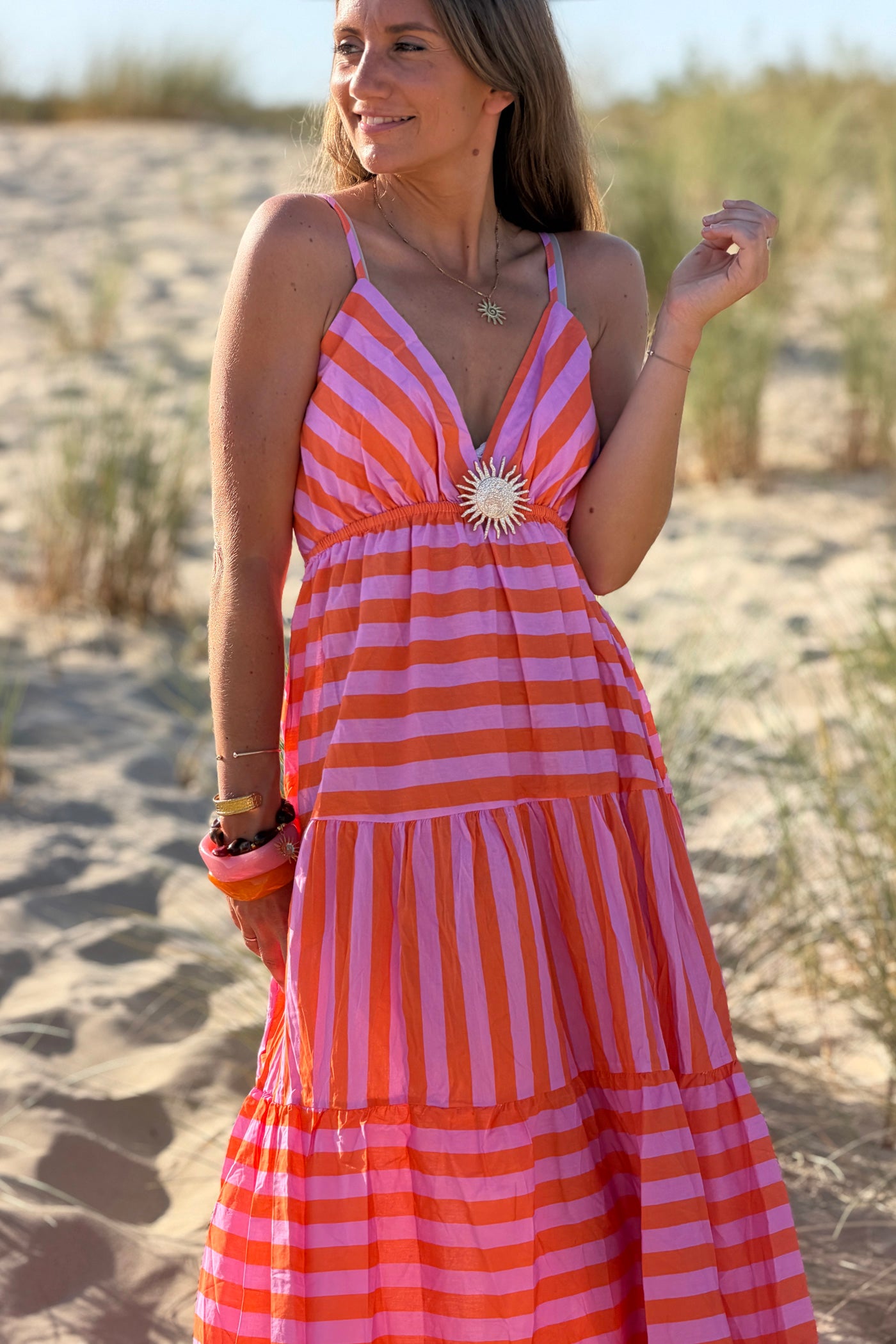 Robe longue à bretelles en coton motifs rayures orange et rose broche soleil doré