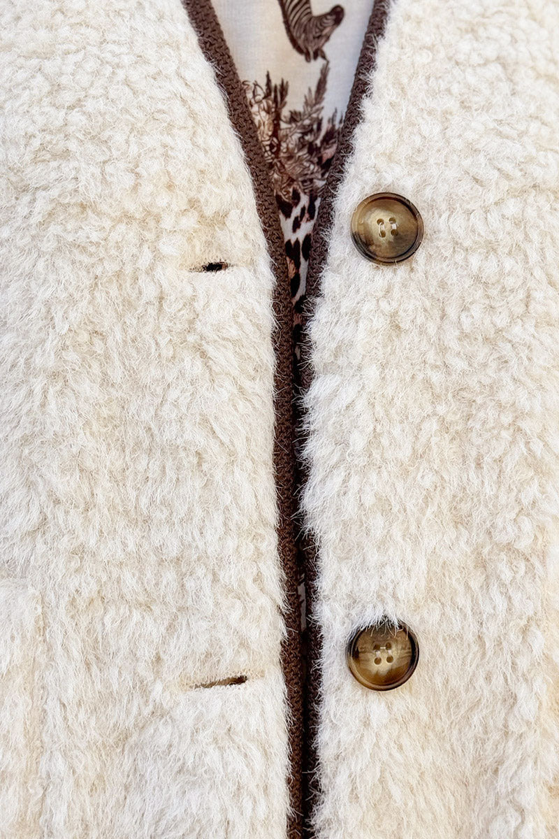 Veste sans manches en moumoute beige détail liseré marron boutons écaille marron